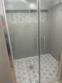 Frameless glass shower with geometric mosaic tile accents and subway tile walls