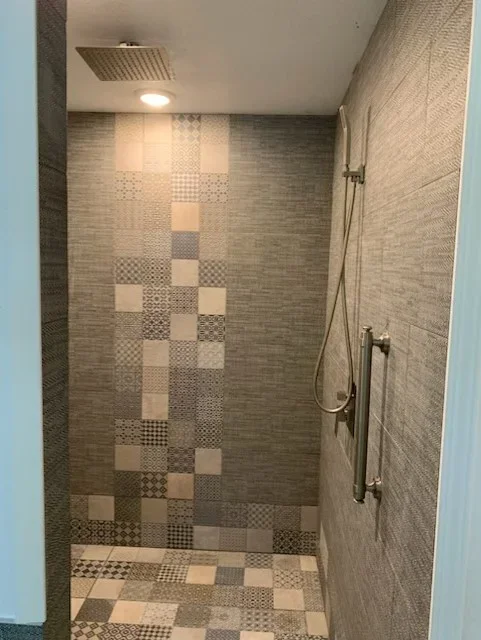 Ceramic tile shower with mixed pattern tiles, rainfall showerhead, and hand-held fixture