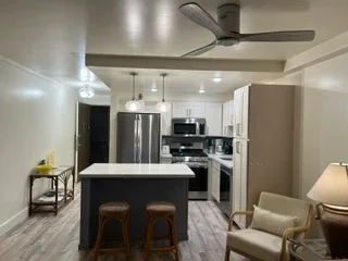 Modern kitchen with black island, stainless steel appliances, white cabinetry, and pendant lighting