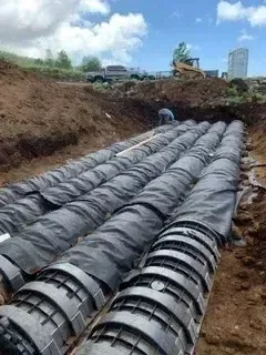 Dual septic leach field lines with perforated drainage pipe and filter fabric wrapping in prepared trench