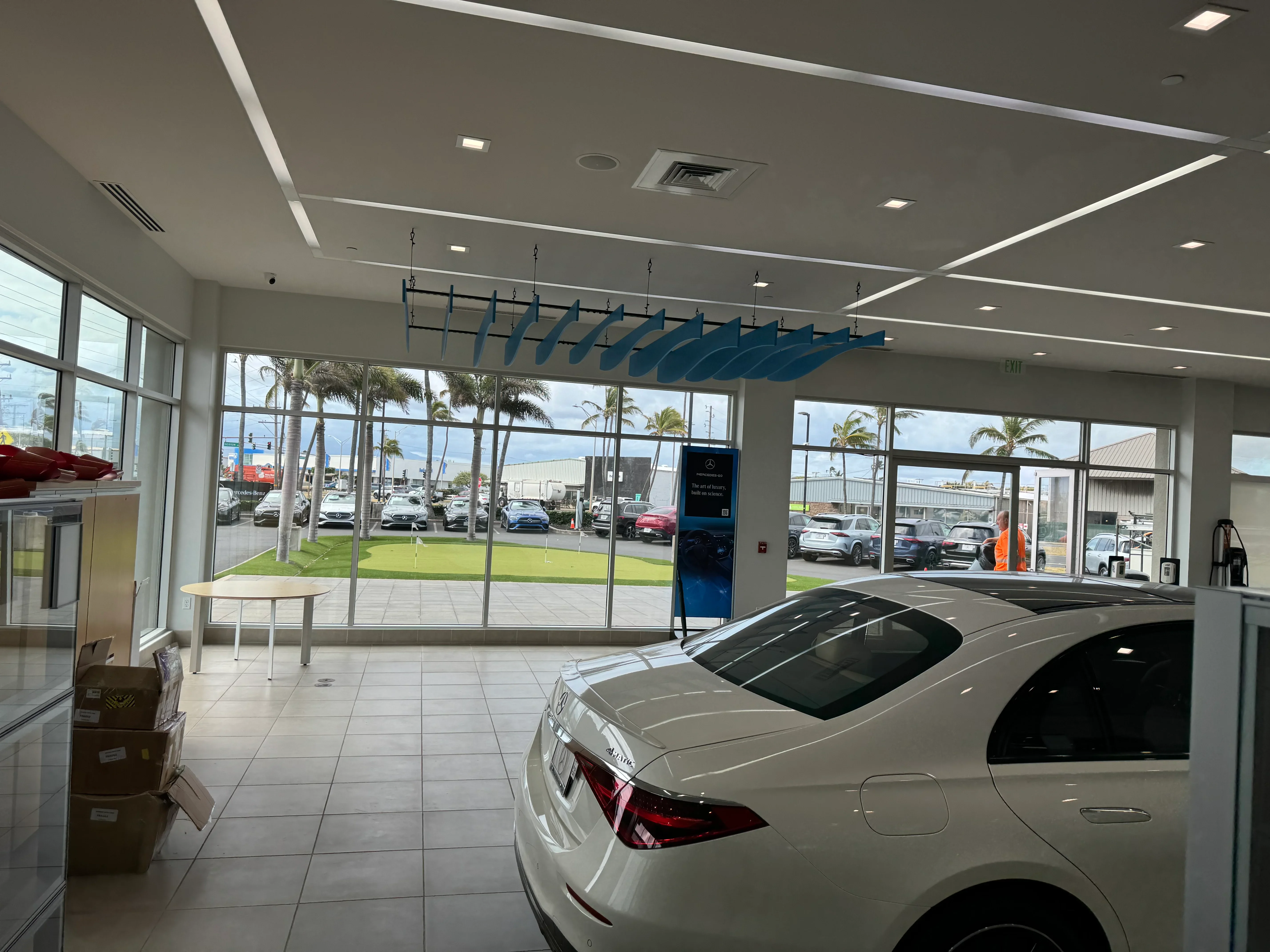 Modern dealership showroom with polished concrete floors, recessed lighting, glass storefront, and suspended blue display fixtures