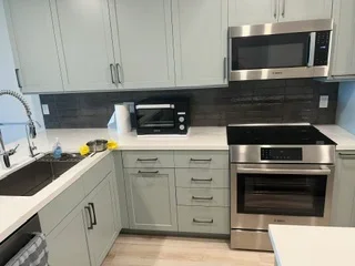 White kitchen cabinets with dark quartz countertops and stainless steel appliances