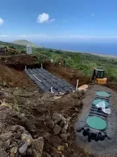 Aerial view of septic tank installation with excavated drainage field and heavy equipment on site