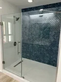 Frameless glass shower enclosure with geometric tile accent wall and brushed nickel hardware