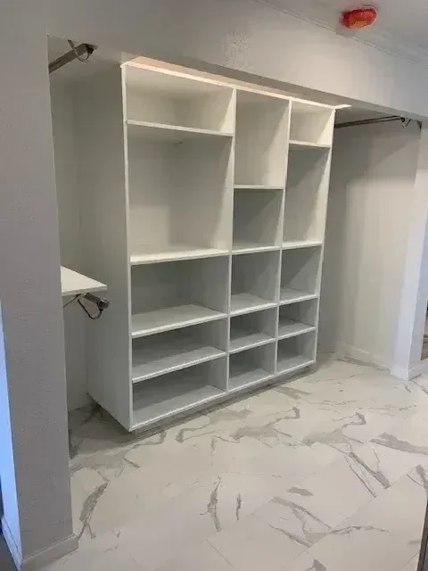 White built-in closet organizer with multiple divided compartments and shelves