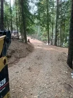 Graded dirt road with compacted soil base and tree-lined edges