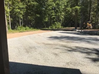 Newly installed gravel driveway with compacted stone surface and tree-lined edges