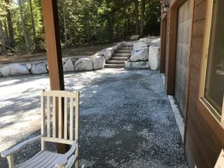 Gravel patio with stacked stone retaining wall steps and wooden post support