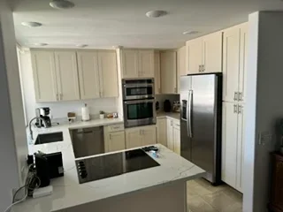 Kitchen with cream cabinetry, stainless steel appliances, quartz island countertop, and recessed lighting