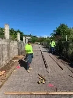 Worker installing interlocking pavers for driveway construction along brick building