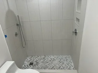 Gray tile shower with herringbone floor pattern and recessed niche